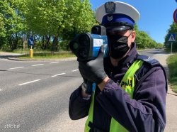 policjant trzymający radar i mierzący prędkość nadjeżdżających pojazdów