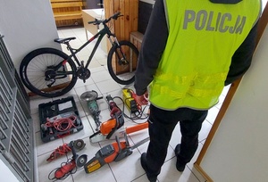 policjant stoi przy elektronarzędziach odzyskanych z kradzieży
